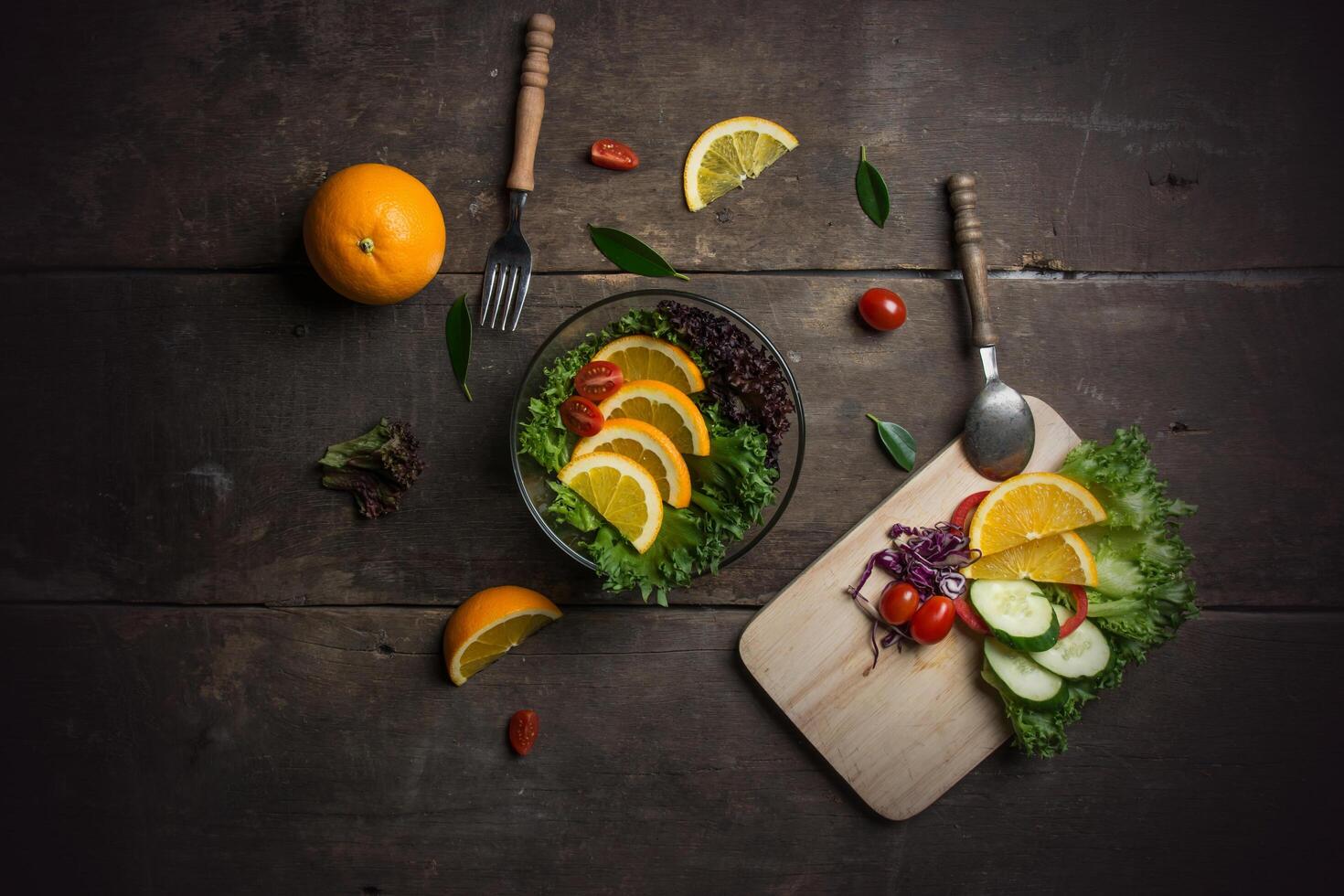 Fresh vegetable salad with sliced orange and tomato on the pan. photo