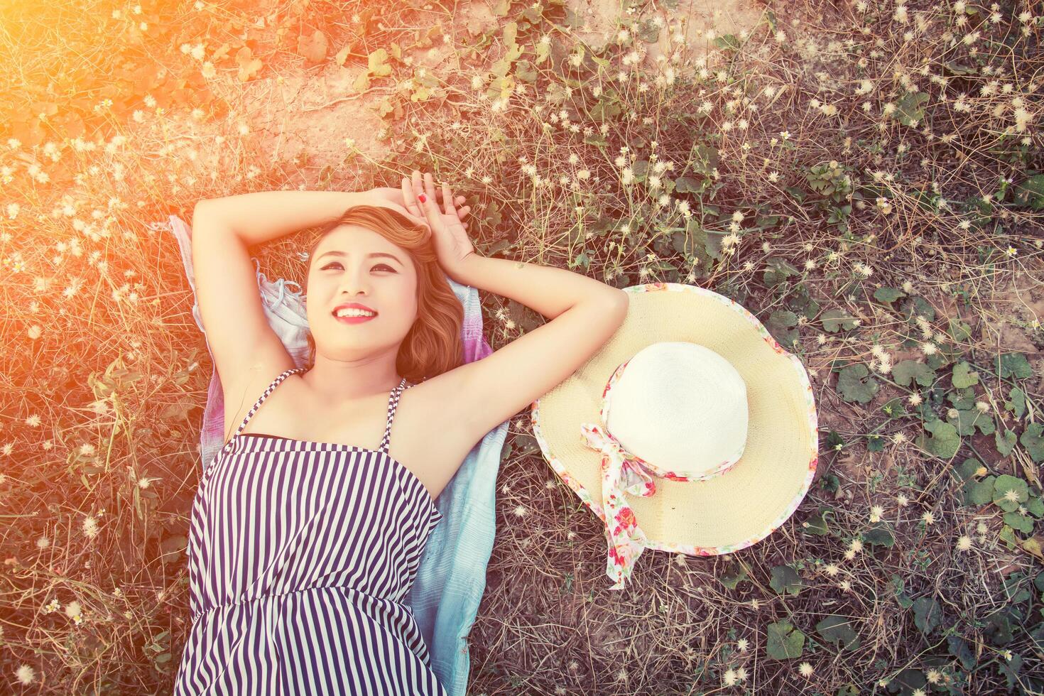 Sexy woman laying listening music from smartphone in the flower field. photo