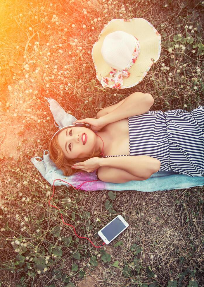 Sexy woman laying listening music from smartphone in the flower field photo