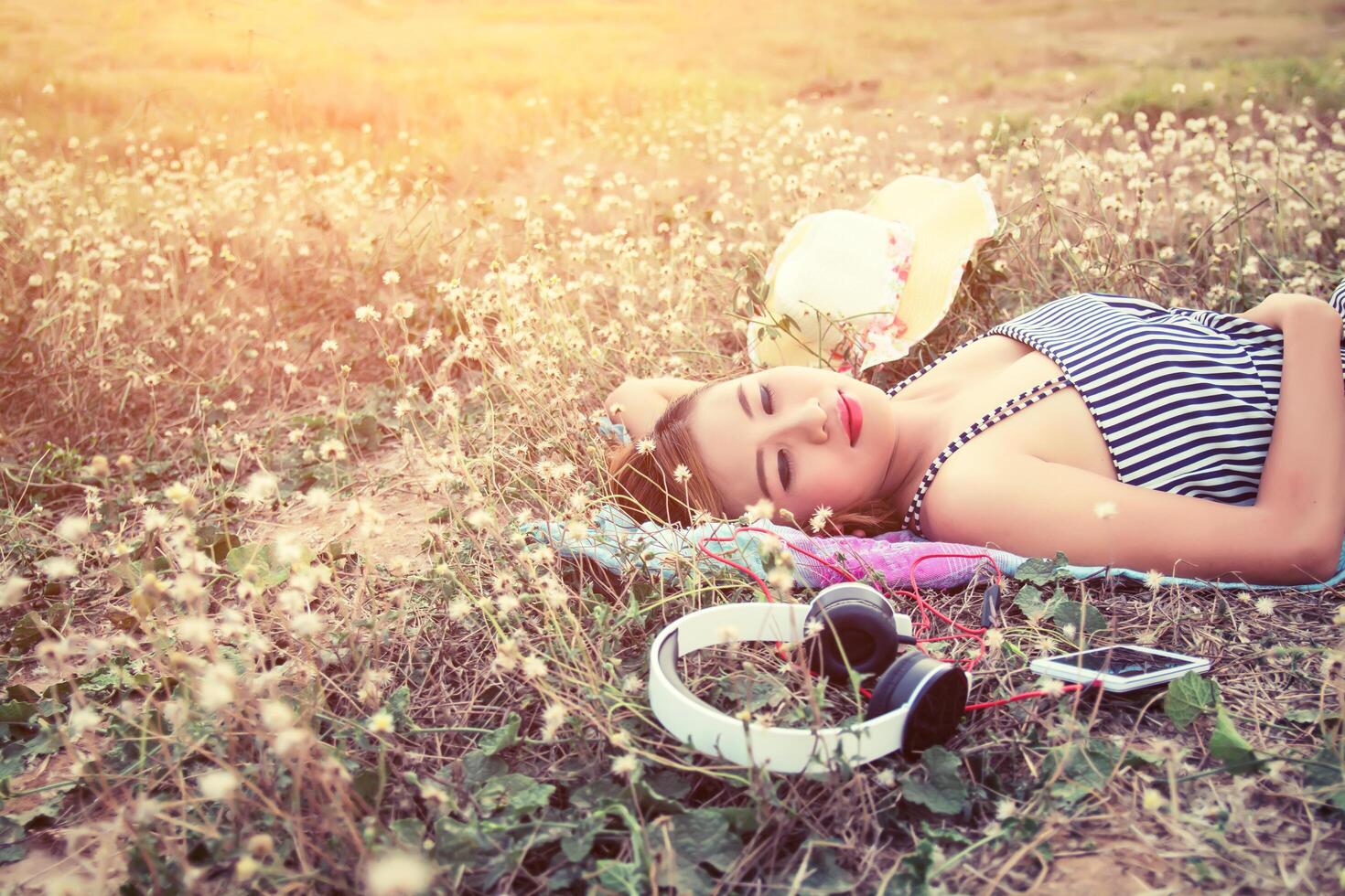 Beautiful sexy young woman lying nearing headphone in the flower field photo