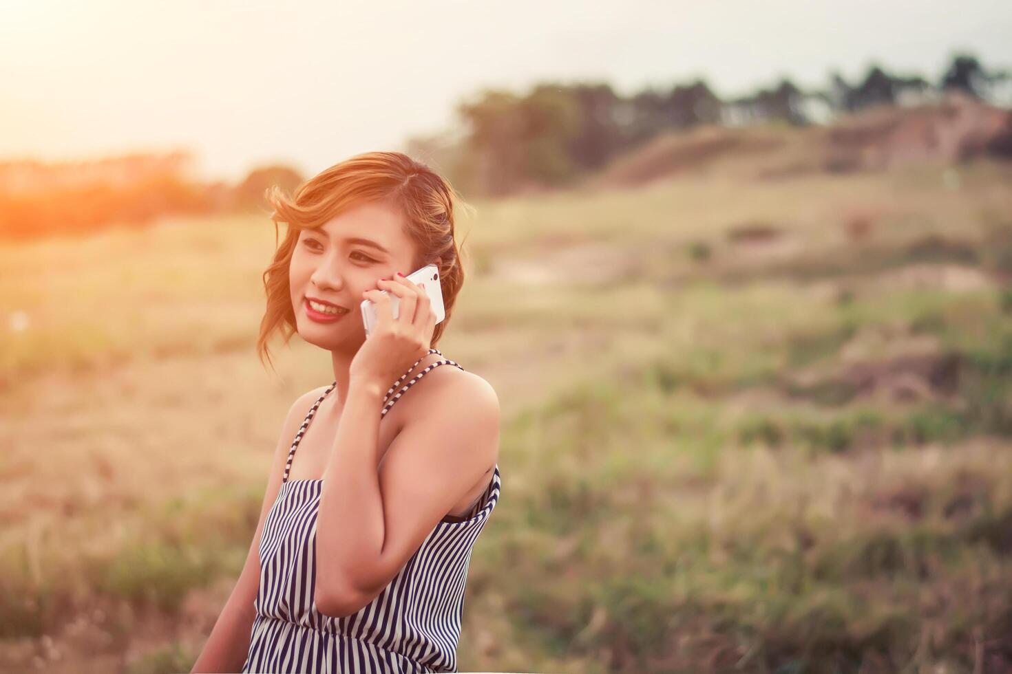 Beautiful sexy woman standing talking on phone in the grass. photo