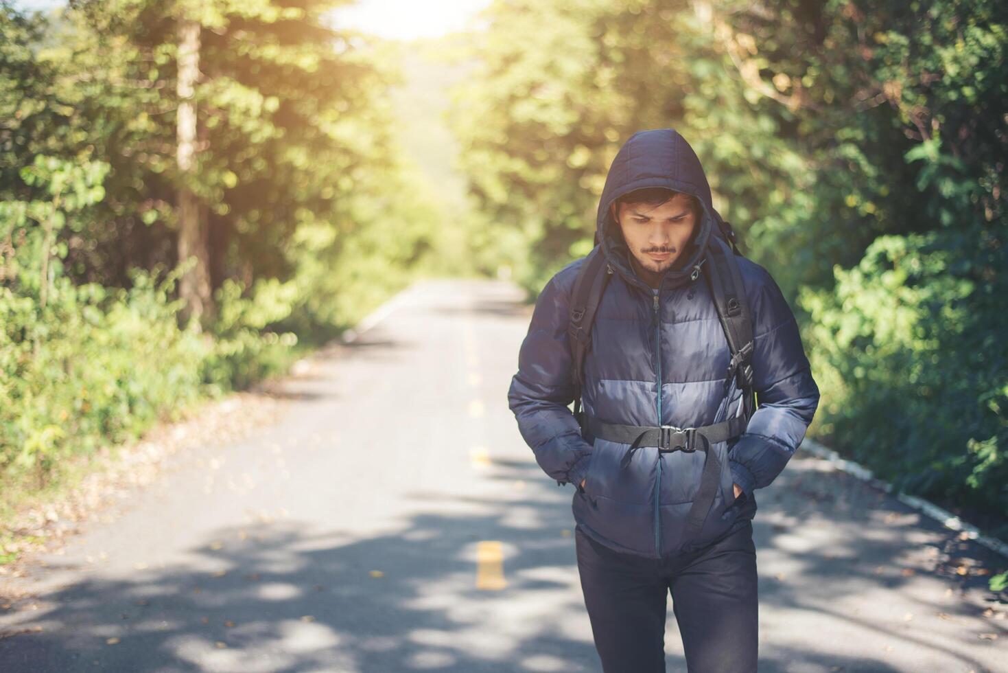 Hiker man walking on the rural road. Holiday tourism concept. photo