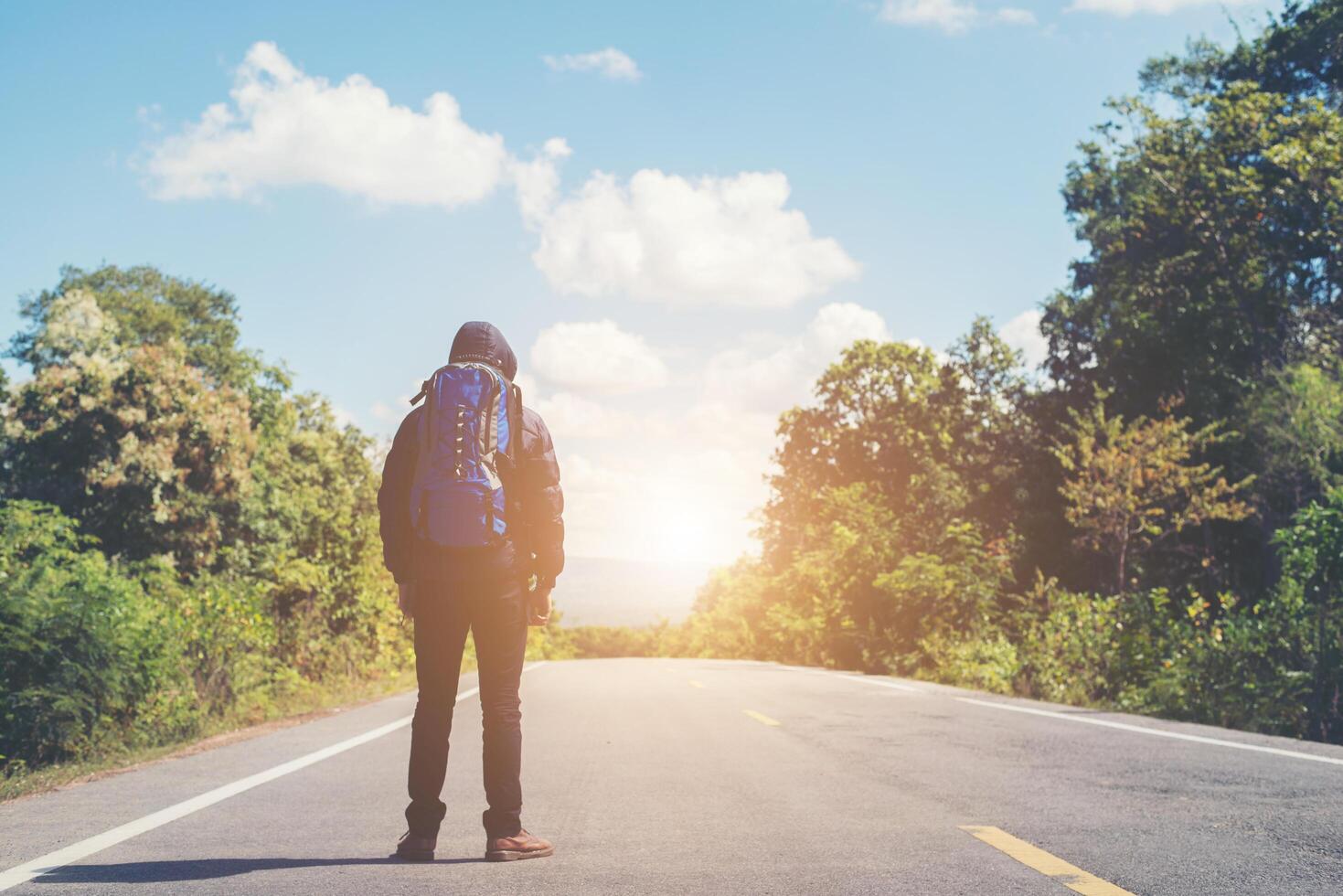 Rear of hiker man walking on the rural road. Holiday tourism concept. photo