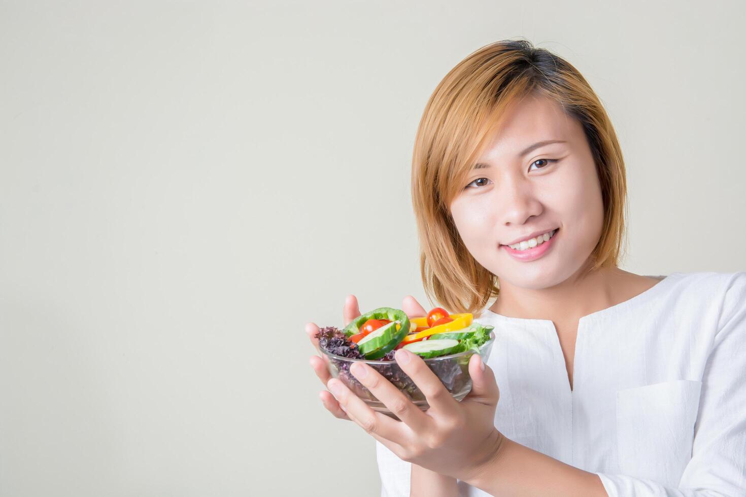 manos de mujer hermosa sosteniendo gran tazón de ensalada de verduras frescas. foto