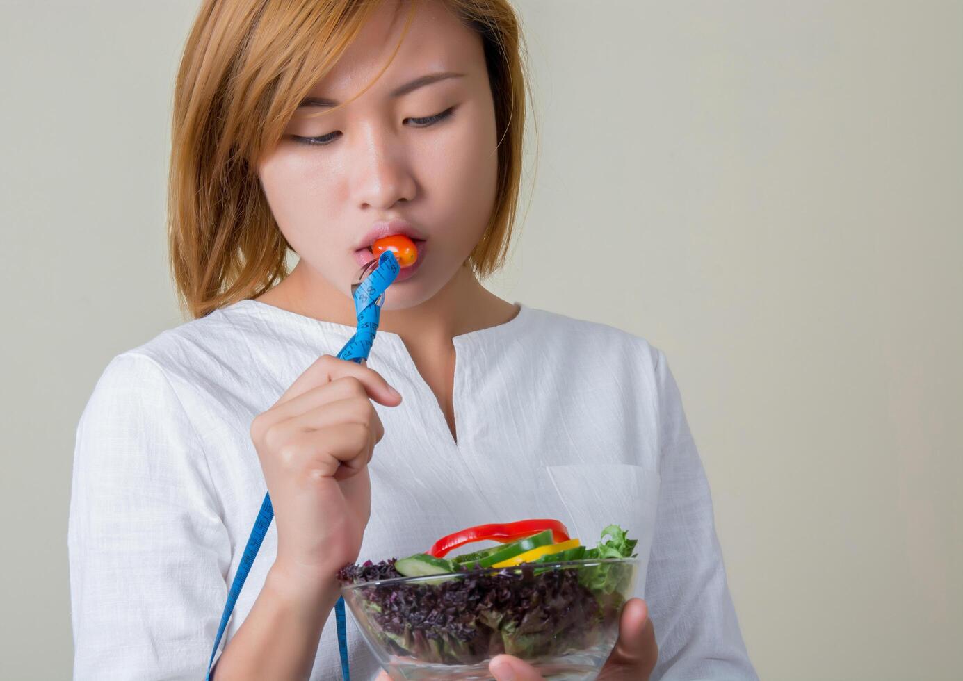 Beautiful woman eating salad with fork tape measure wrapped. photo