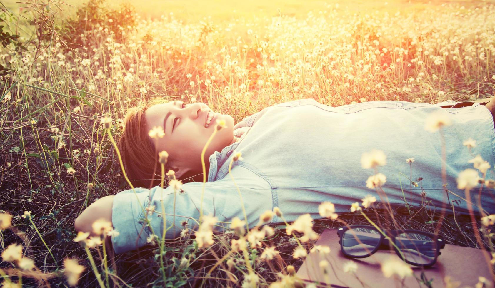 Young hipster laying down on the dandelion field smiley into the sky. photo