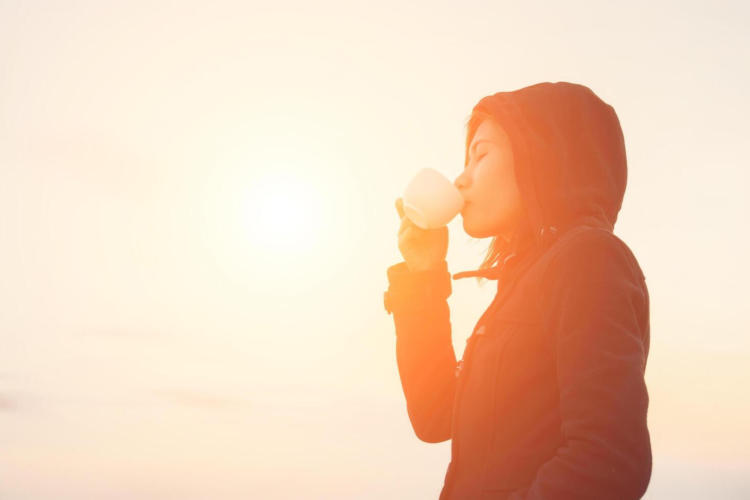 mujer joven bebiendo una taza de café con la salida del sol por la mañana. foto