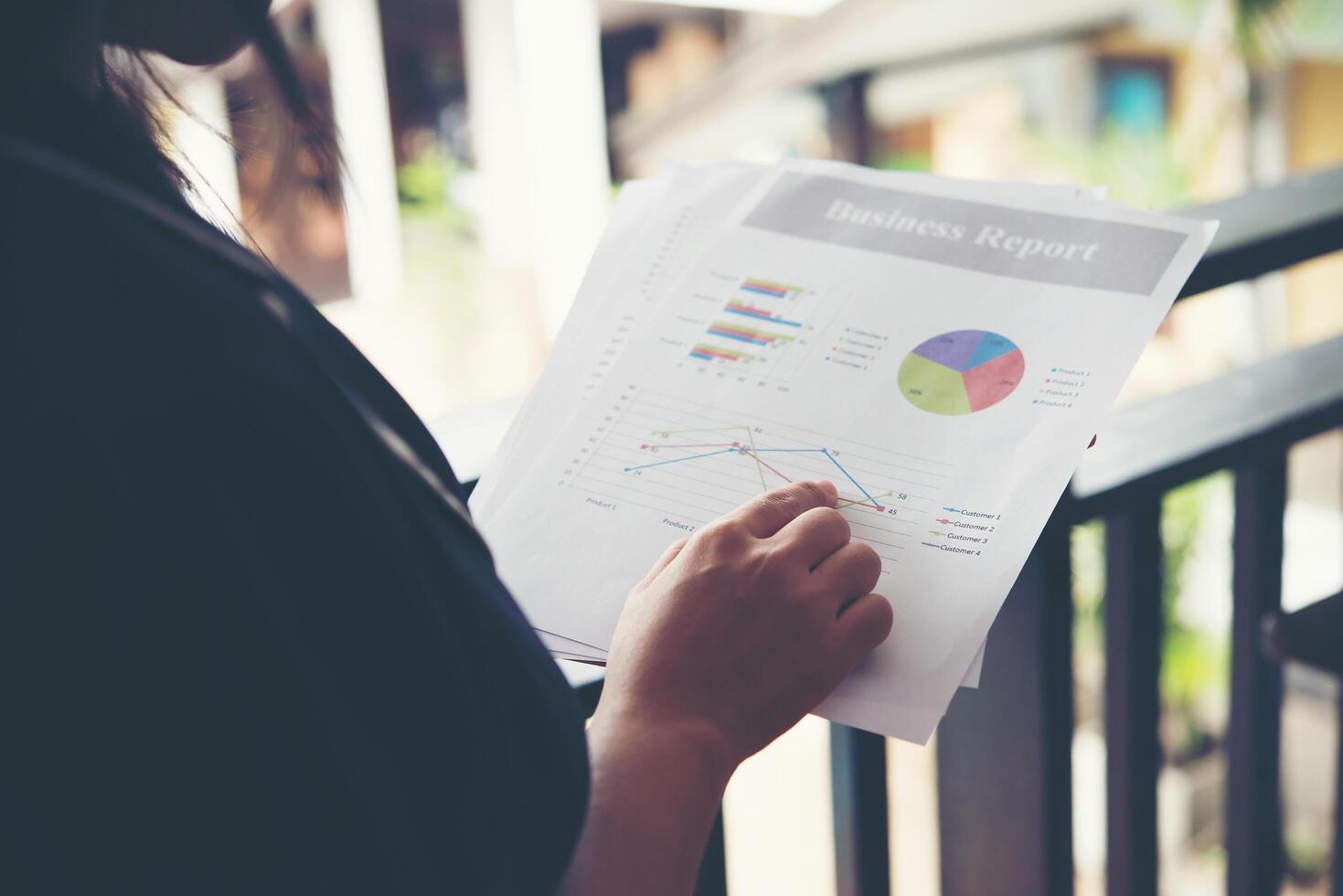 Hands of financial woman pointing on finance chart notes while working photo