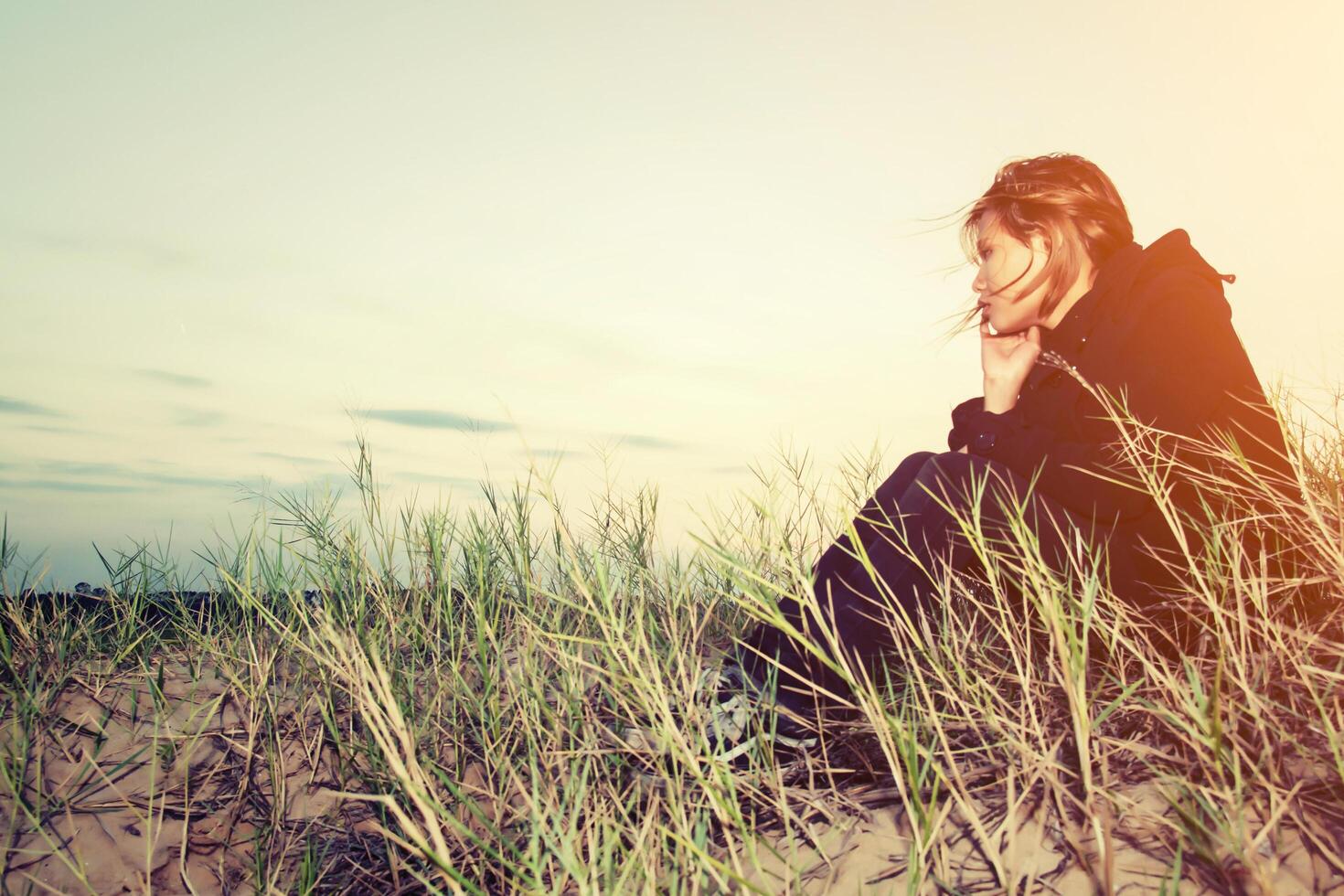 Sad young girl sitting alone on a grass outdoors,Sadness. Loneliness photo