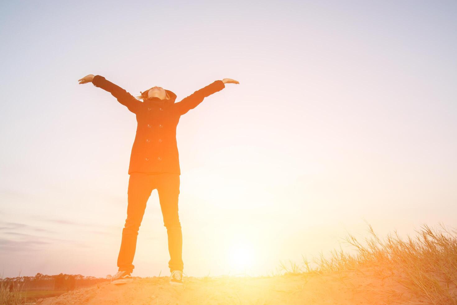 Young woman open arms under the sunrise at mountain photo