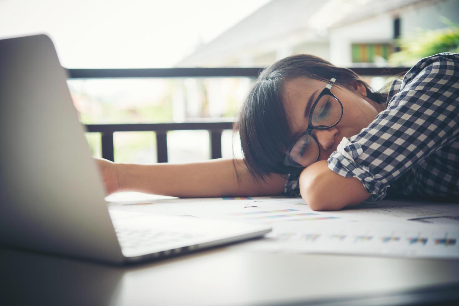 Mujer de negocios cansada dormida en una computadora portátil mientras trabajaba en su lugar de trabajo foto