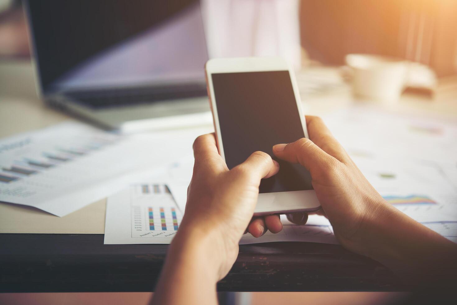 manos de mujer de negocios escribiendo en el teléfono móvil mientras trabaja. foto