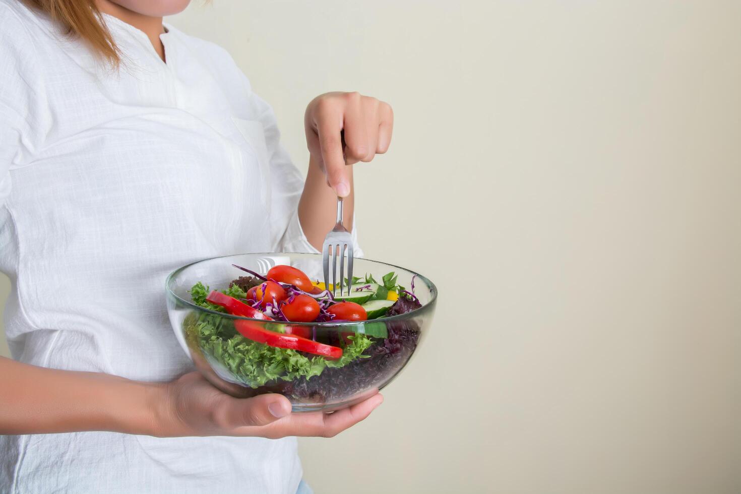 hands of beautiful woman holding big bowl of fresh veggie salad. photo