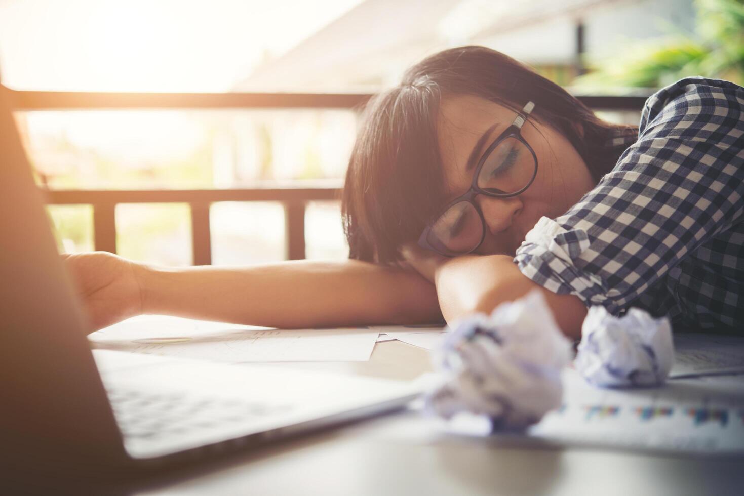 Tired business woman asleep on a laptop while working in her workplace photo