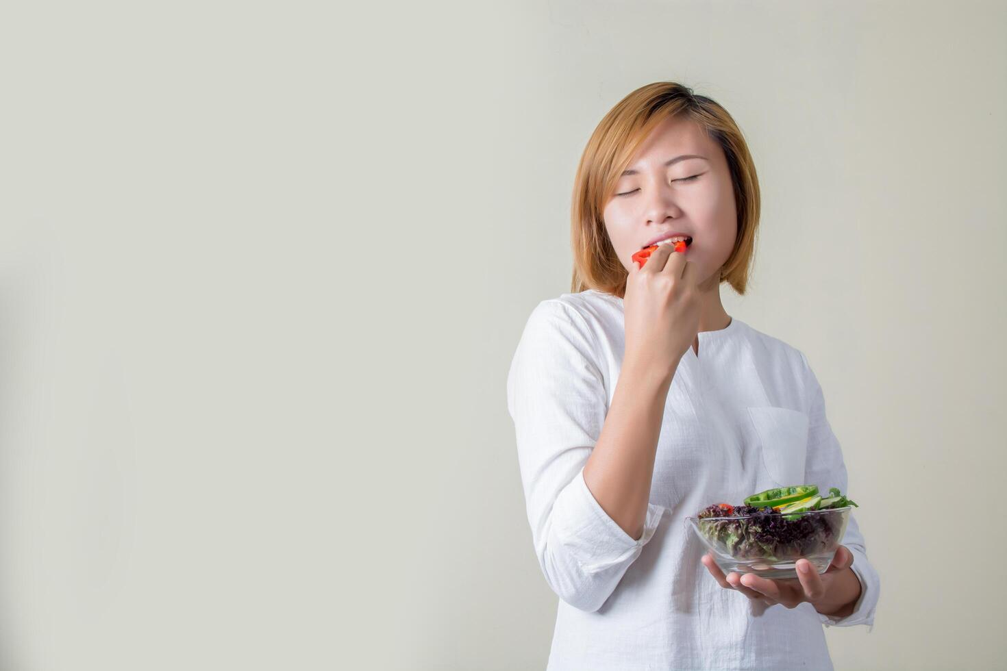 beautiful woman standing holding bowl of salad eating some vegetable photo