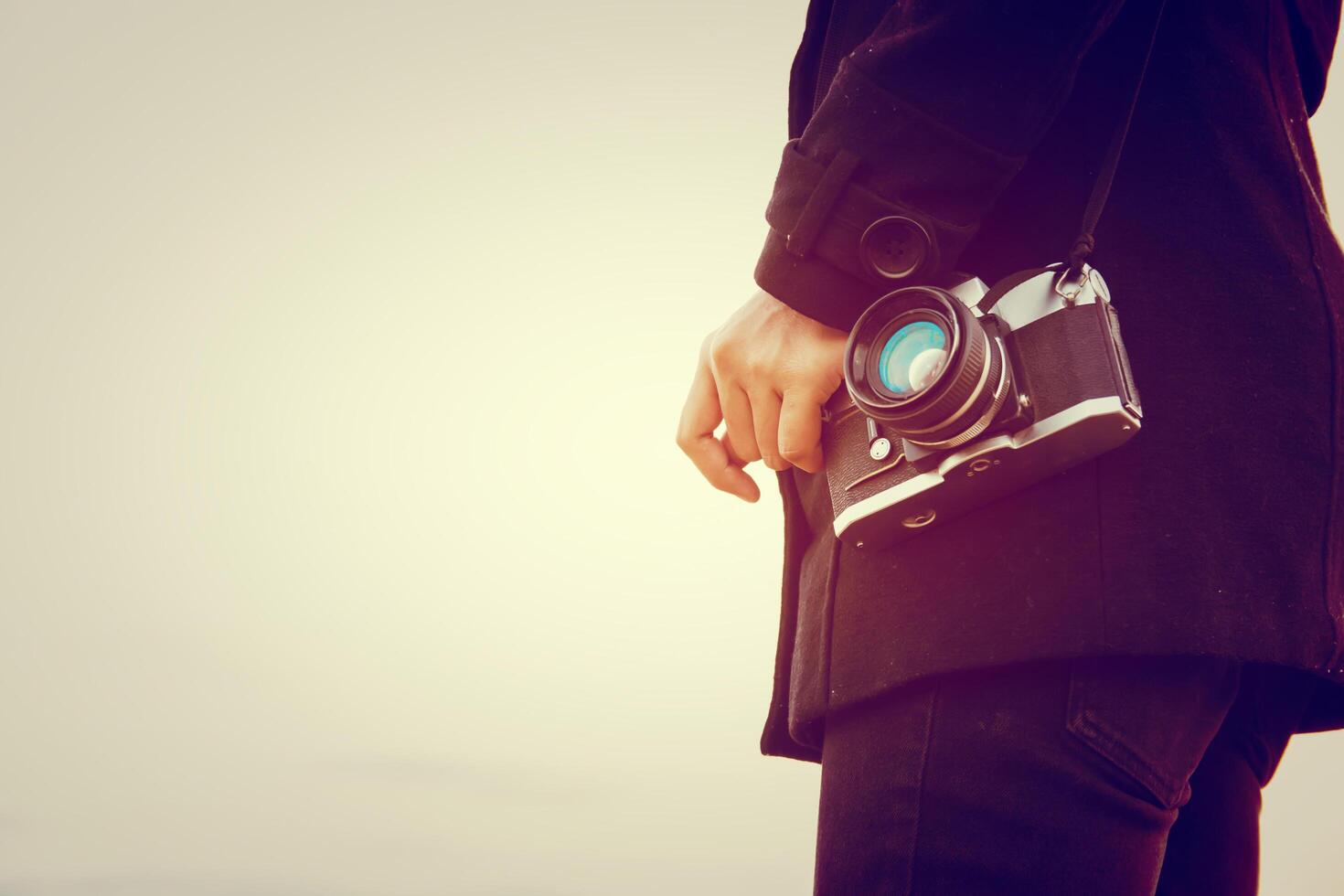 Young woman wearing black coat standing carry retro camera photo