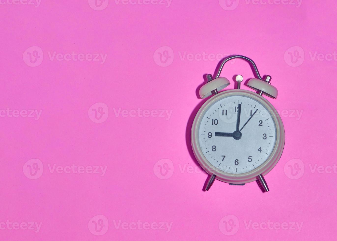 vintage alarm clock on light pink background photo