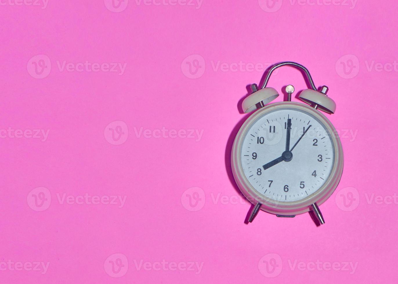 Despertador vintage sobre fondo rosa claro foto