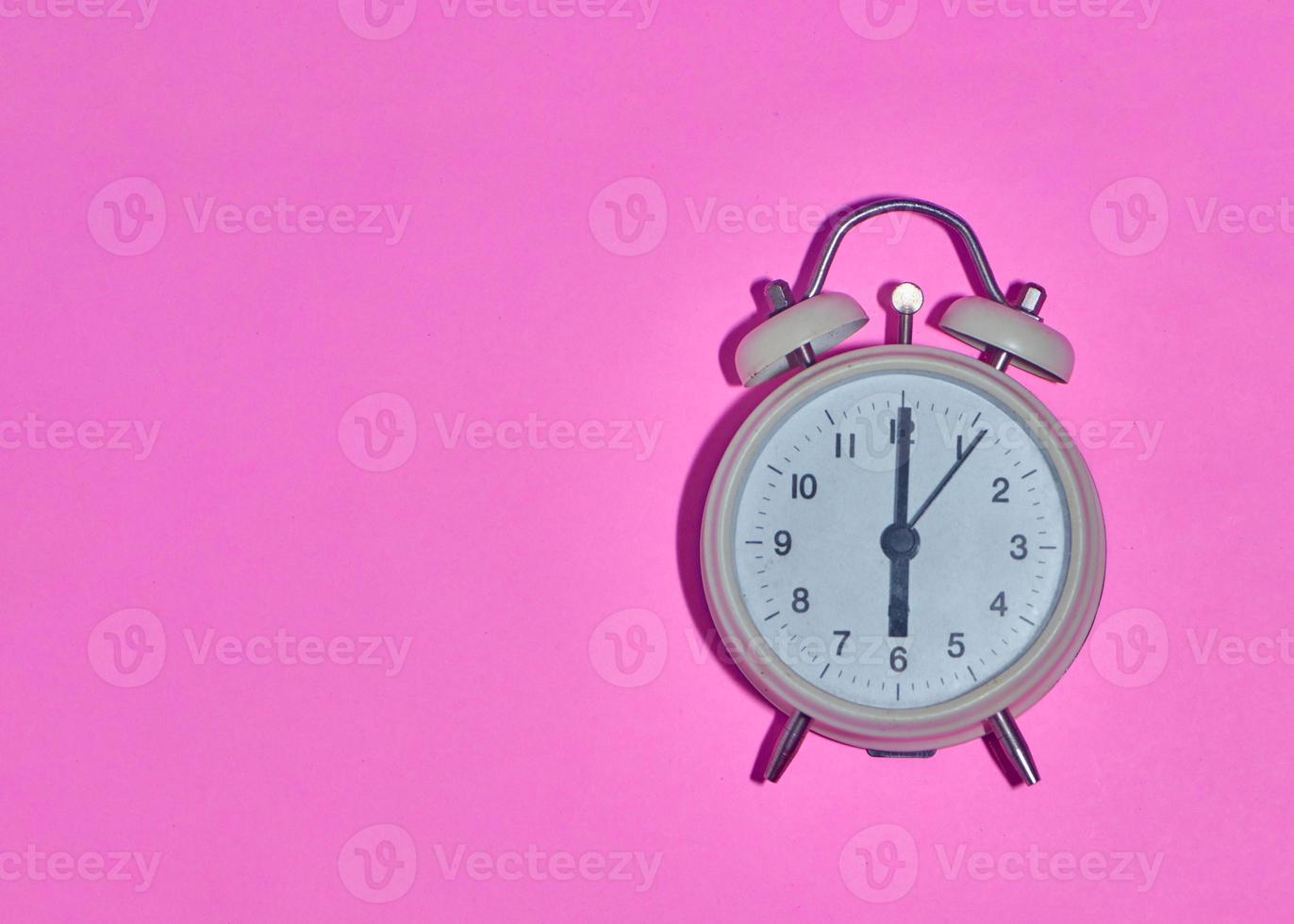 vintage alarm clock on light pink background photo