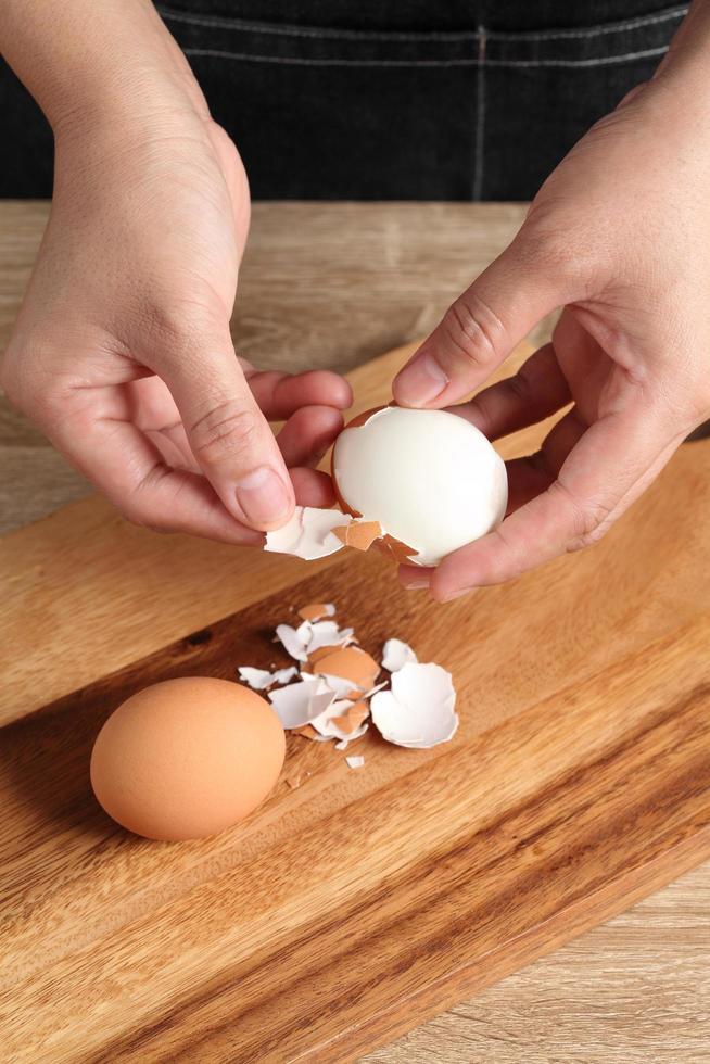 Chef peeling boiled egg on wooden cutting board photo