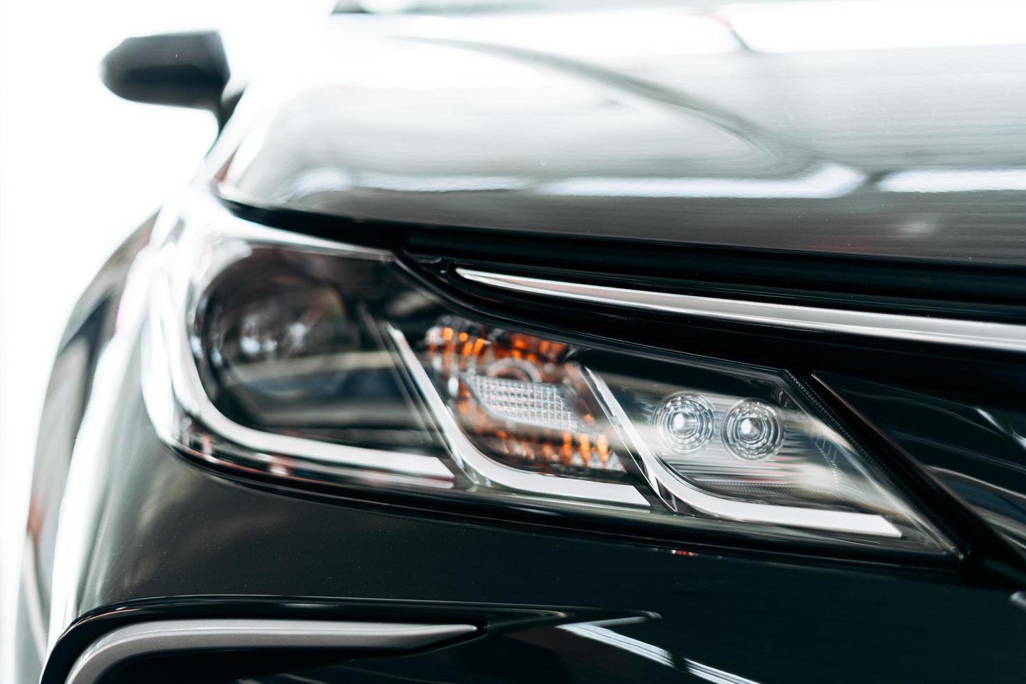 Closeup of a headlight on a modern black car with reflection. photo