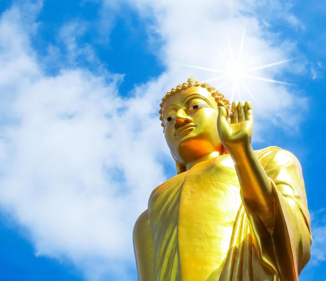 Golden Buddha statue outdoors on blue sky background. photo