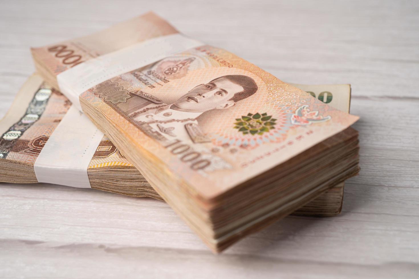 Stack of Thai baht banknotes on wooden background photo