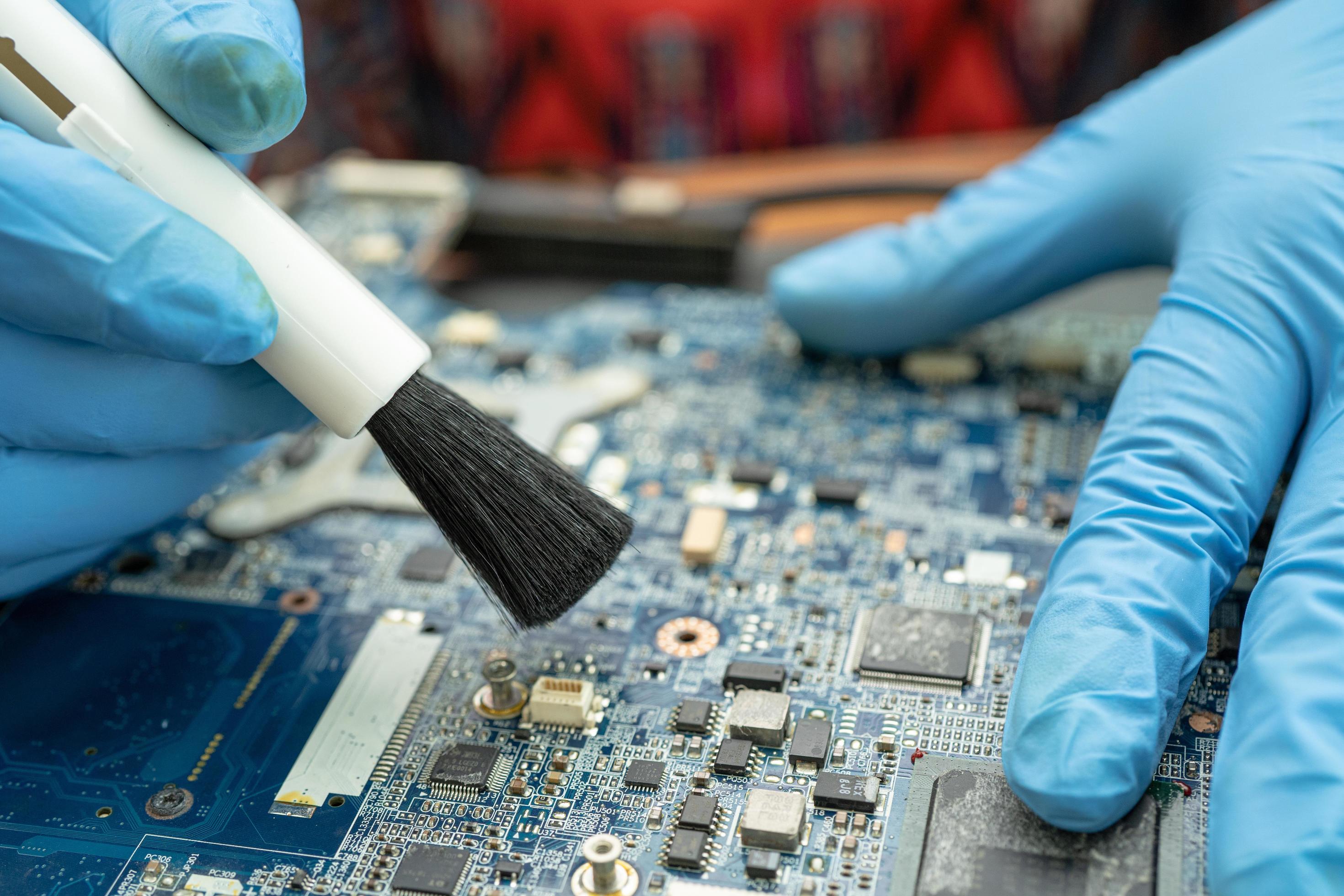 Technician use brush to clean dust in circuit board computer. 3115095