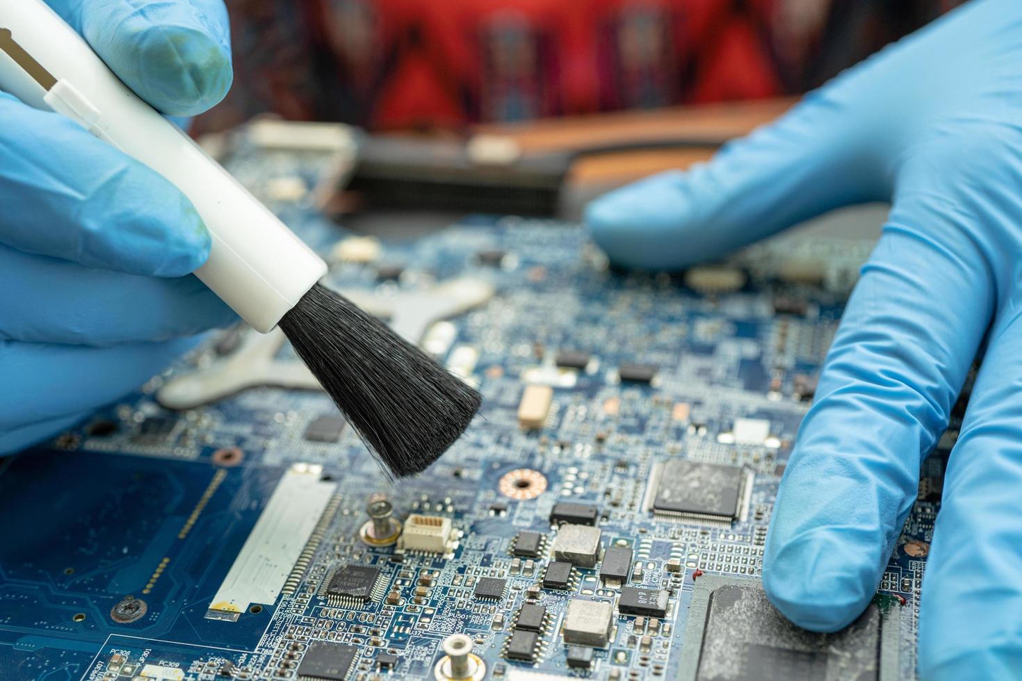 El técnico usa un cepillo para limpiar el polvo en la placa de circuito de la computadora. foto