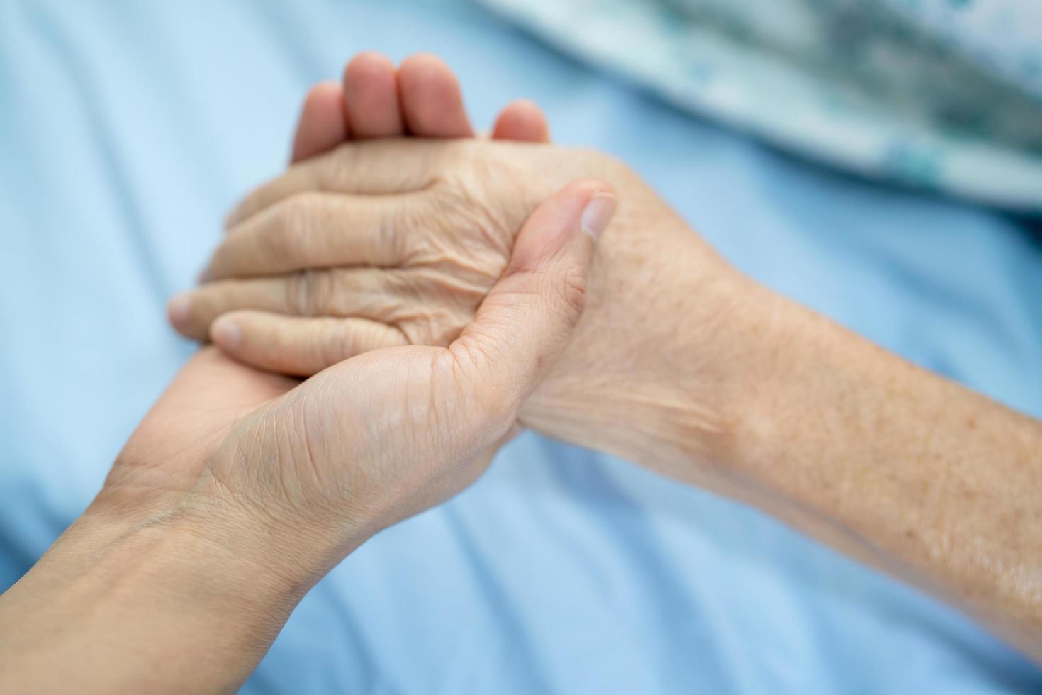 Doctor sosteniendo tocar las manos paciente mujer senior asiática con amor foto