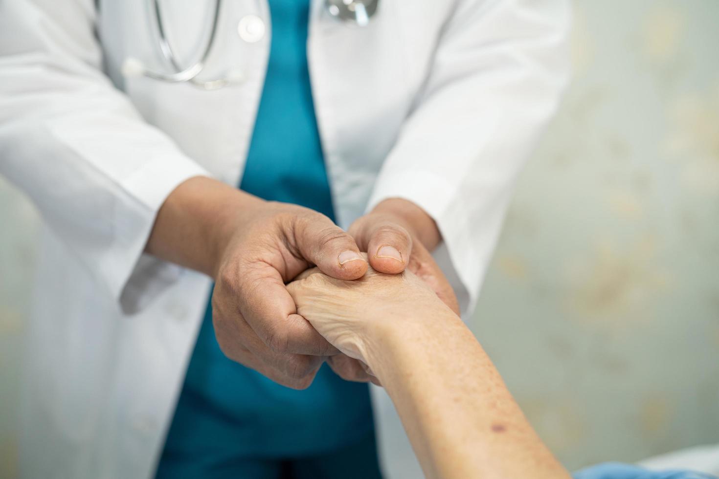 Doctor sosteniendo las manos conmovedoras paciente mujer mayor asiática con amor, foto