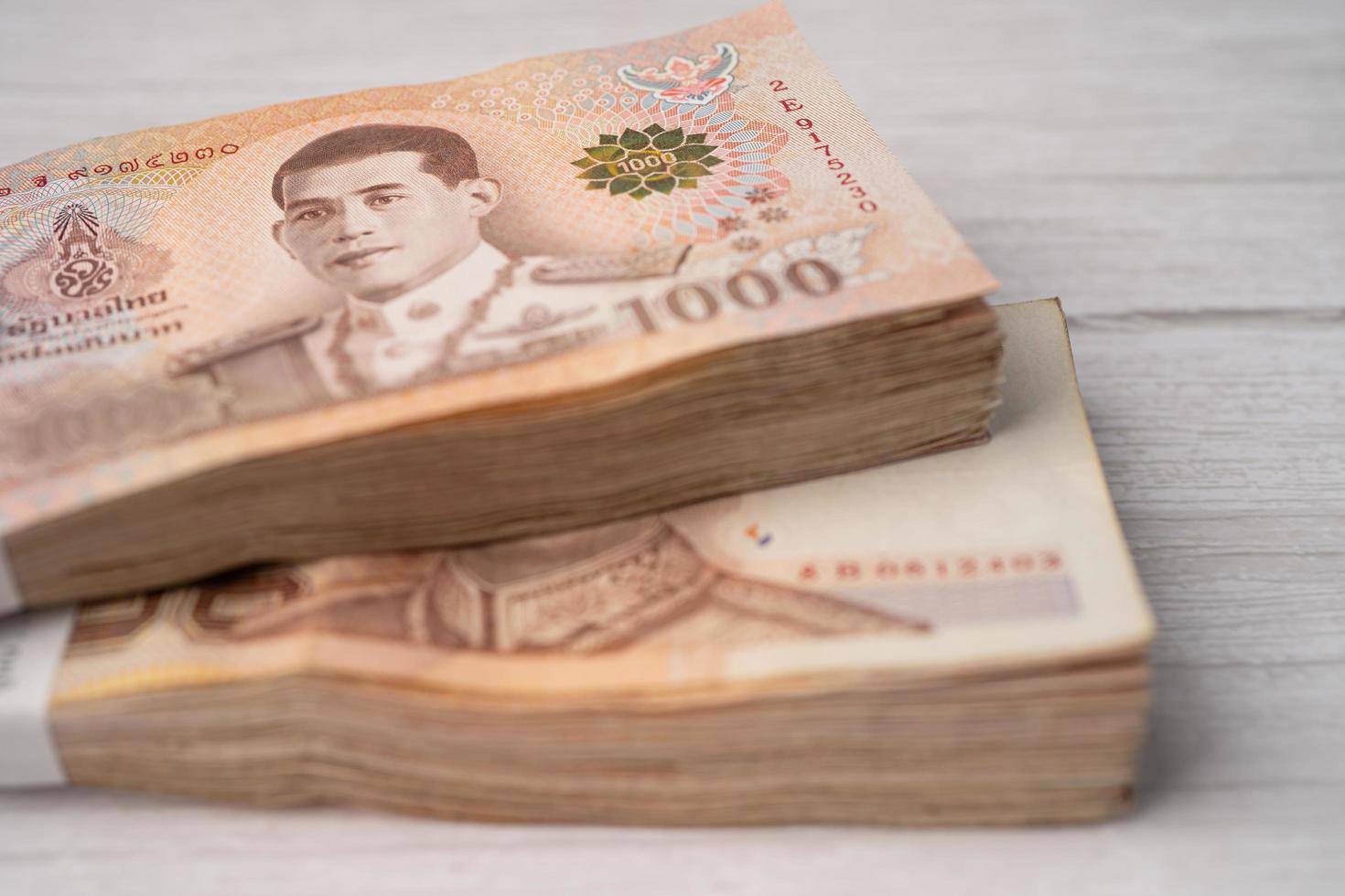 Stack of Thai baht banknotes on wooden background, photo