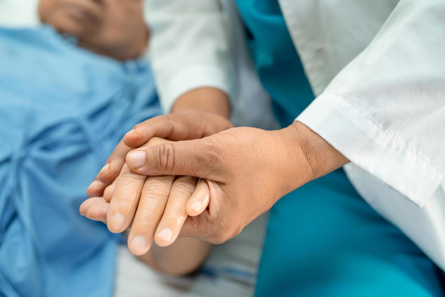 Doctor sosteniendo tocar las manos paciente mujer senior asiática con amor foto