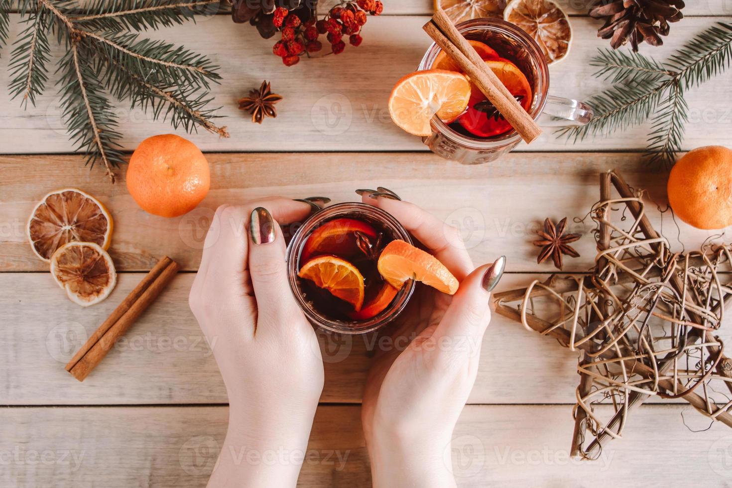Woman holds cup of hot mulled wine in her hands photo