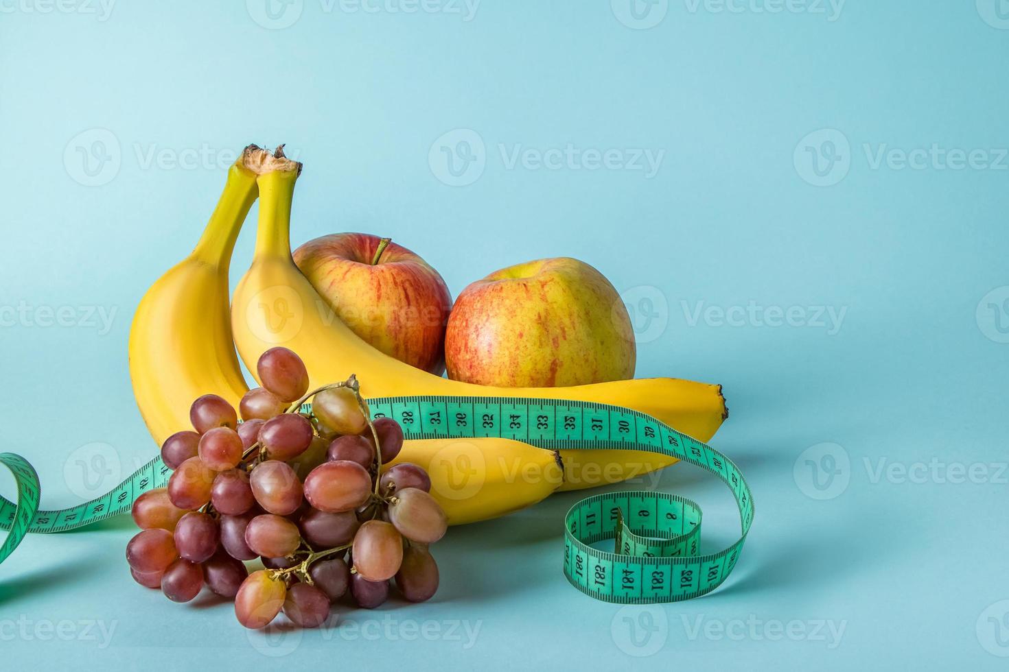 Frutas maduras y cinta métrica sobre un fondo azul. foto