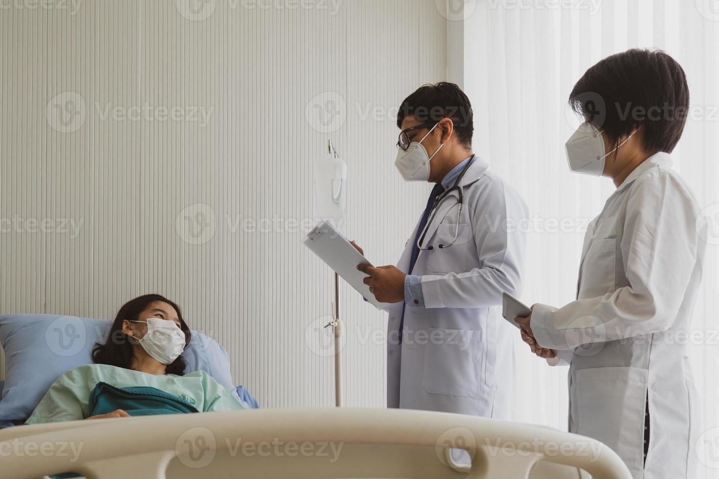 Médico y estudiante de medicina visitan al paciente en la sala del hospital. foto