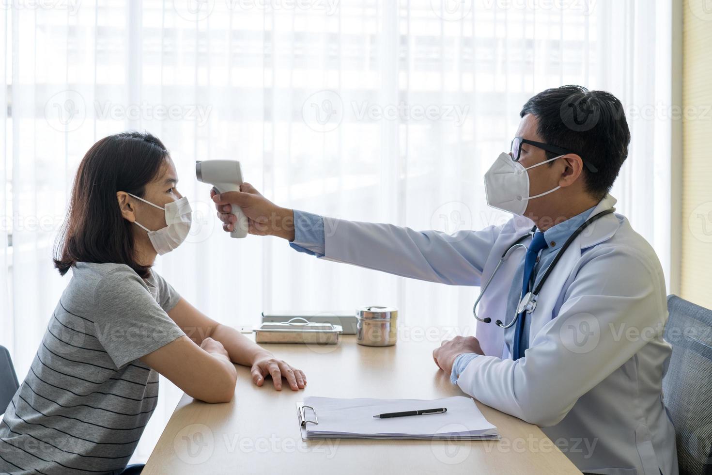 Médico con termómetro digital para medir la temperatura del paciente. foto