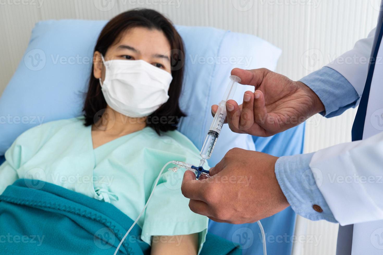 Doctor dando líquido intravenoso a un paciente asiático en la sala foto