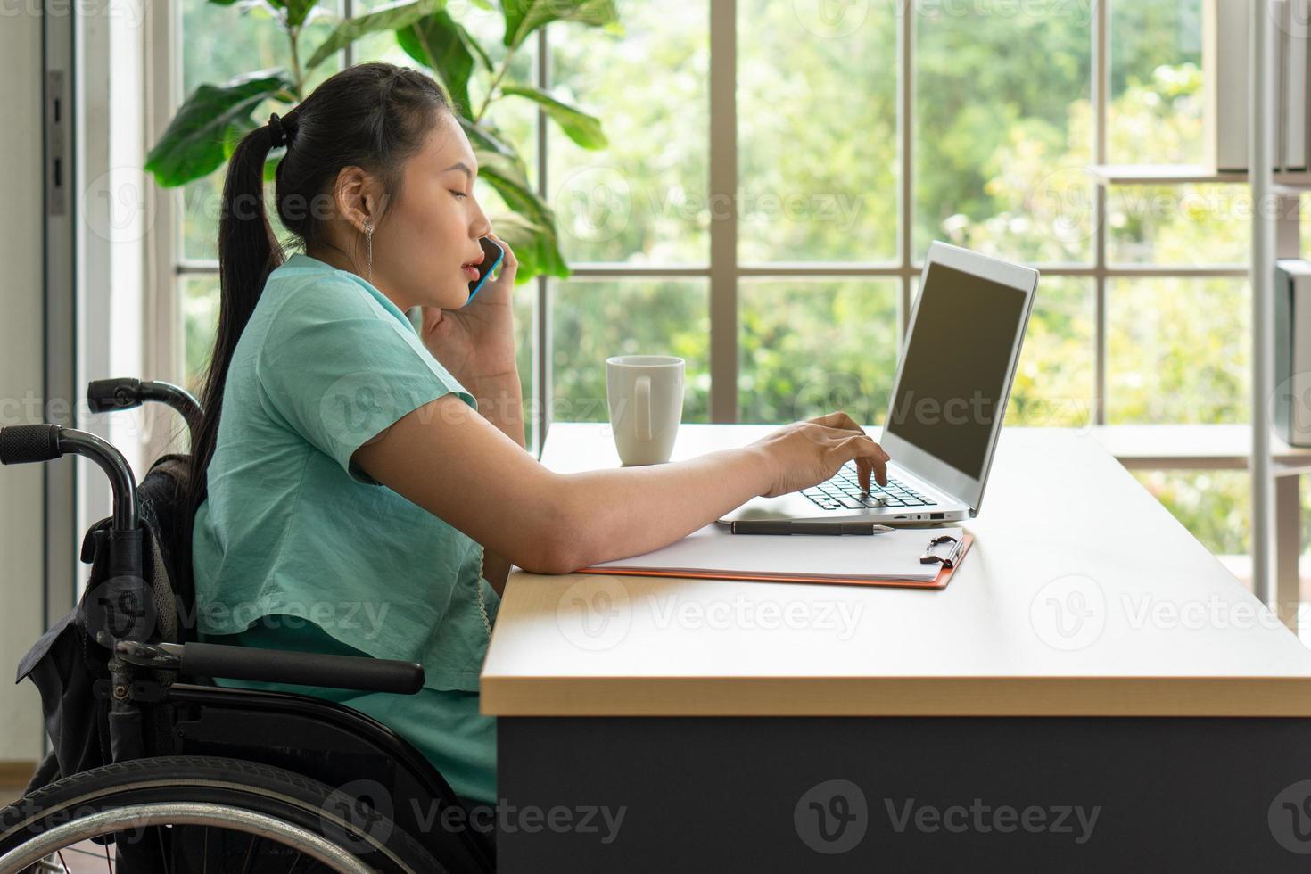 Joven mujer discapacitada con ordenador y smartphone para trabajar en la oficina foto