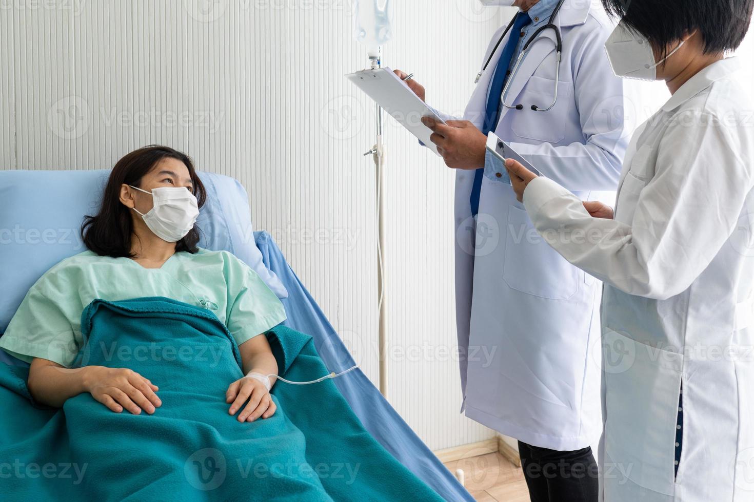 Médico y estudiante de medicina visitan al paciente en la sala del hospital. foto