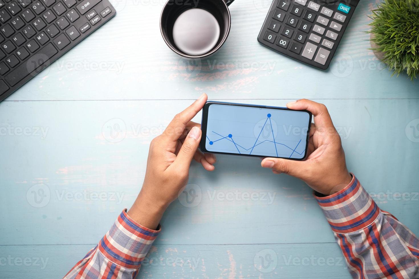 Joven analizando el gráfico de cotizaciones en teléfonos inteligentes. foto