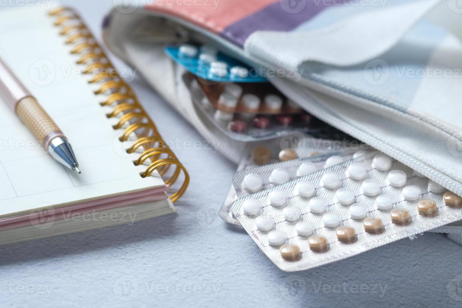 Pastillas anticonceptivas en una bolsa con un planificador en la mesa foto