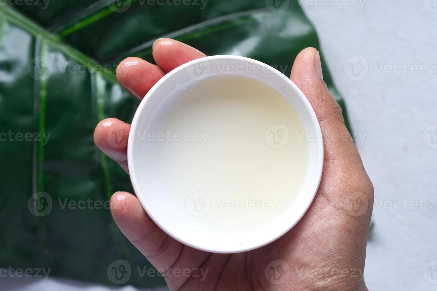 man hand hold coconut oil container close up photo