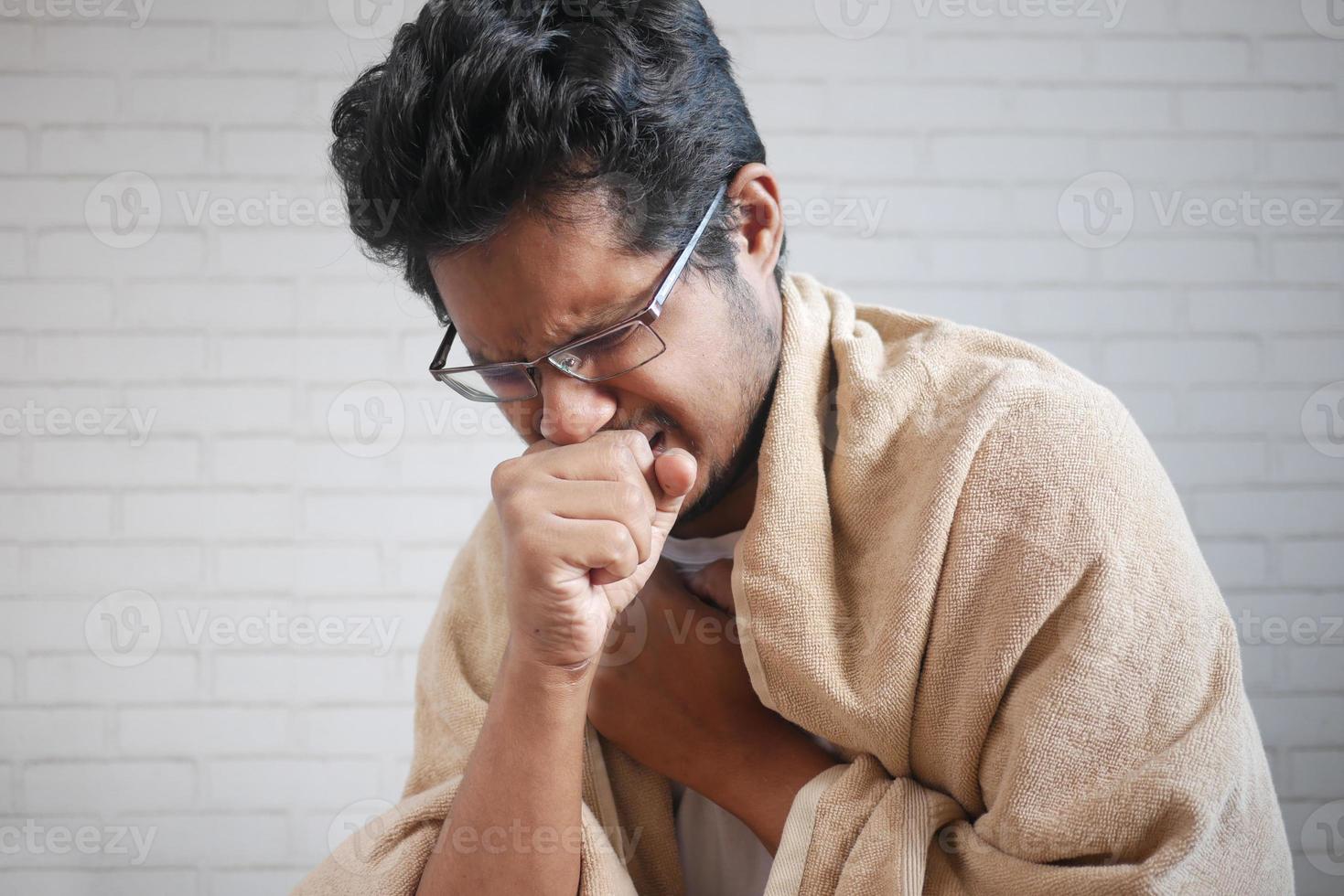 Mature man in blanket coughing while sited on bed photo