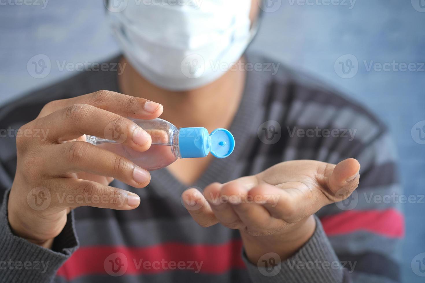 man in face mask using sanitizer liquid for preventing corona virus photo