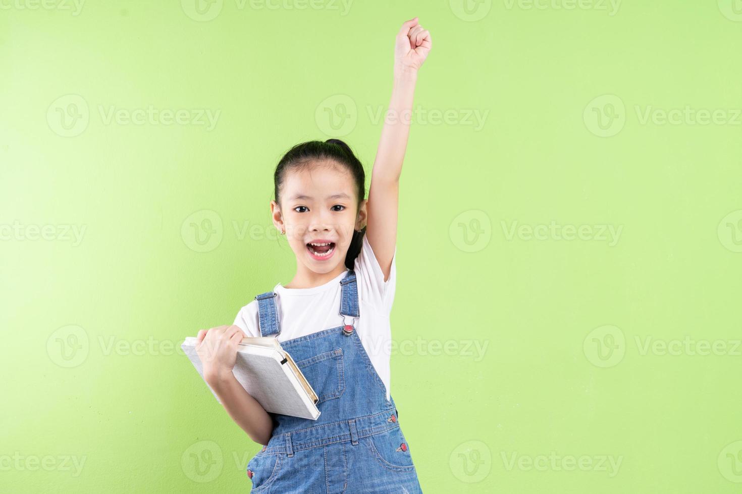 Portrait of Asian child holding book on green background photo