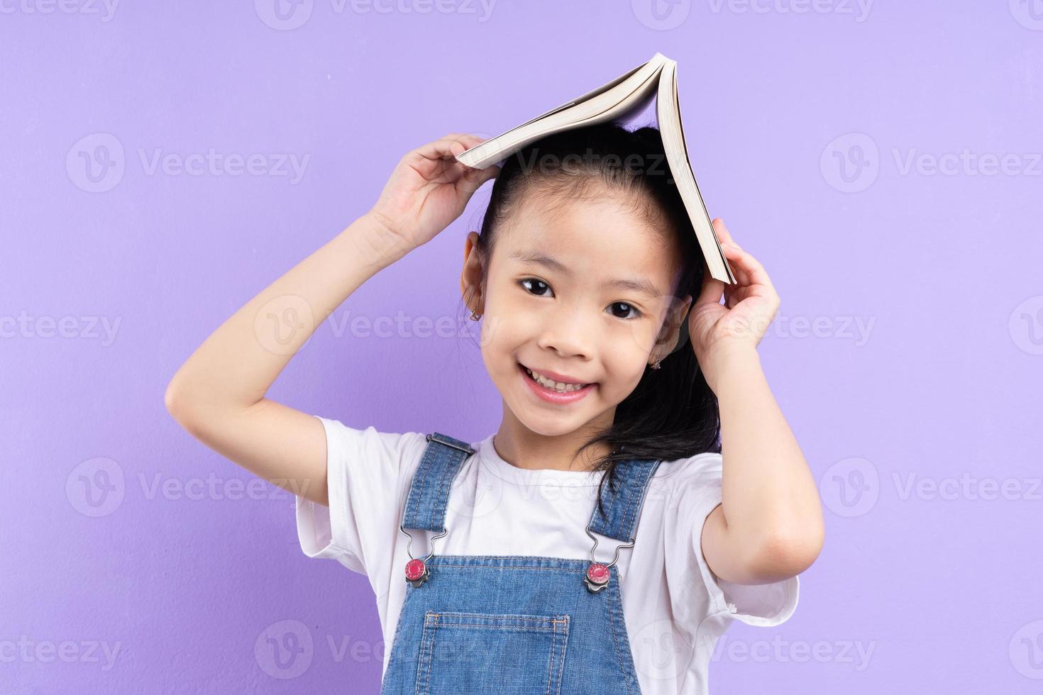 retrato, de, asiático, niño, tenencia, libro, en, fondo púrpura foto