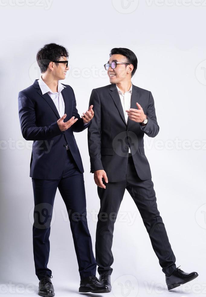 Two Asian businessmen walking on white background photo