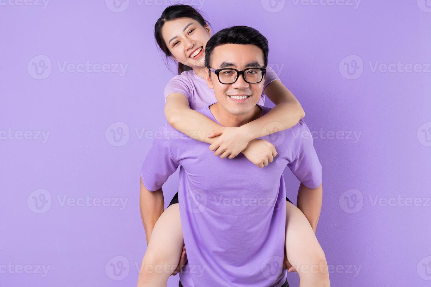 Young Asian couple posing on purple background photo