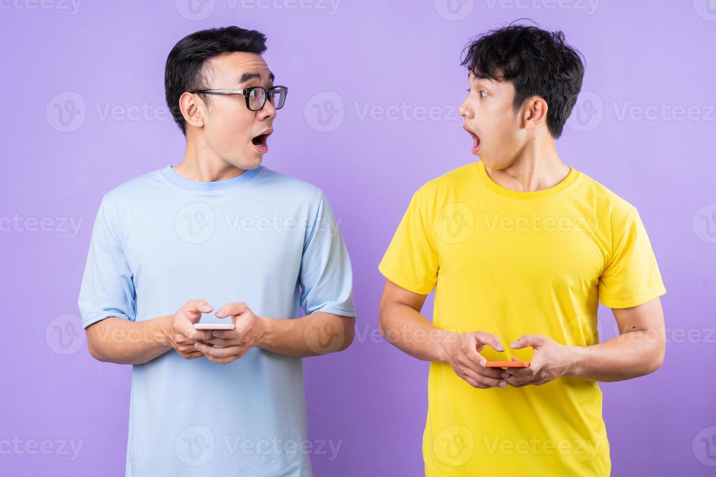 Two Asian brothers using cell phones on purple background photo